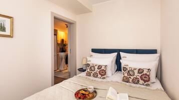 A bedroom with a bed, pillows, a tray with food and drink, and an open book.