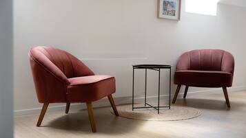 Twee fauteuils met houten poten en een klein tafeltje met een metalen frame, staand op een houten vloer met een geweven vloerkleed.