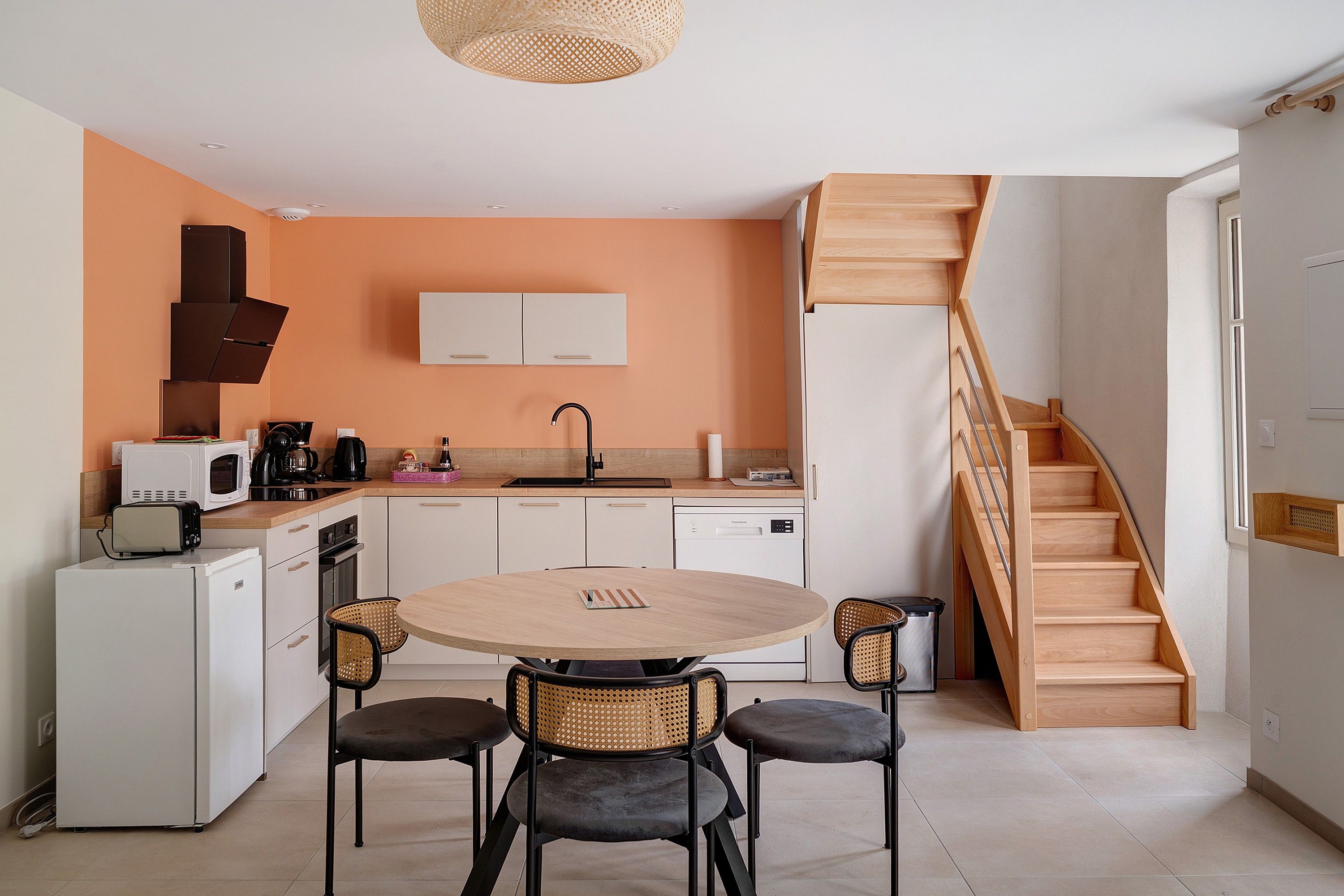 A compact kitchen with a round table and four chairs, a microwave, a toaster, and a coffee maker.