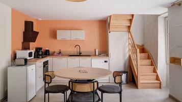 A compact kitchen with a round table and four chairs, a microwave, a toaster, and a coffee maker.