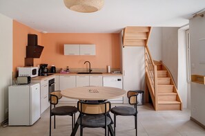 Une cuisine compacte avec une table ronde et quatre chaises, un four à micro-ondes, un grille-pain et une machine à café.