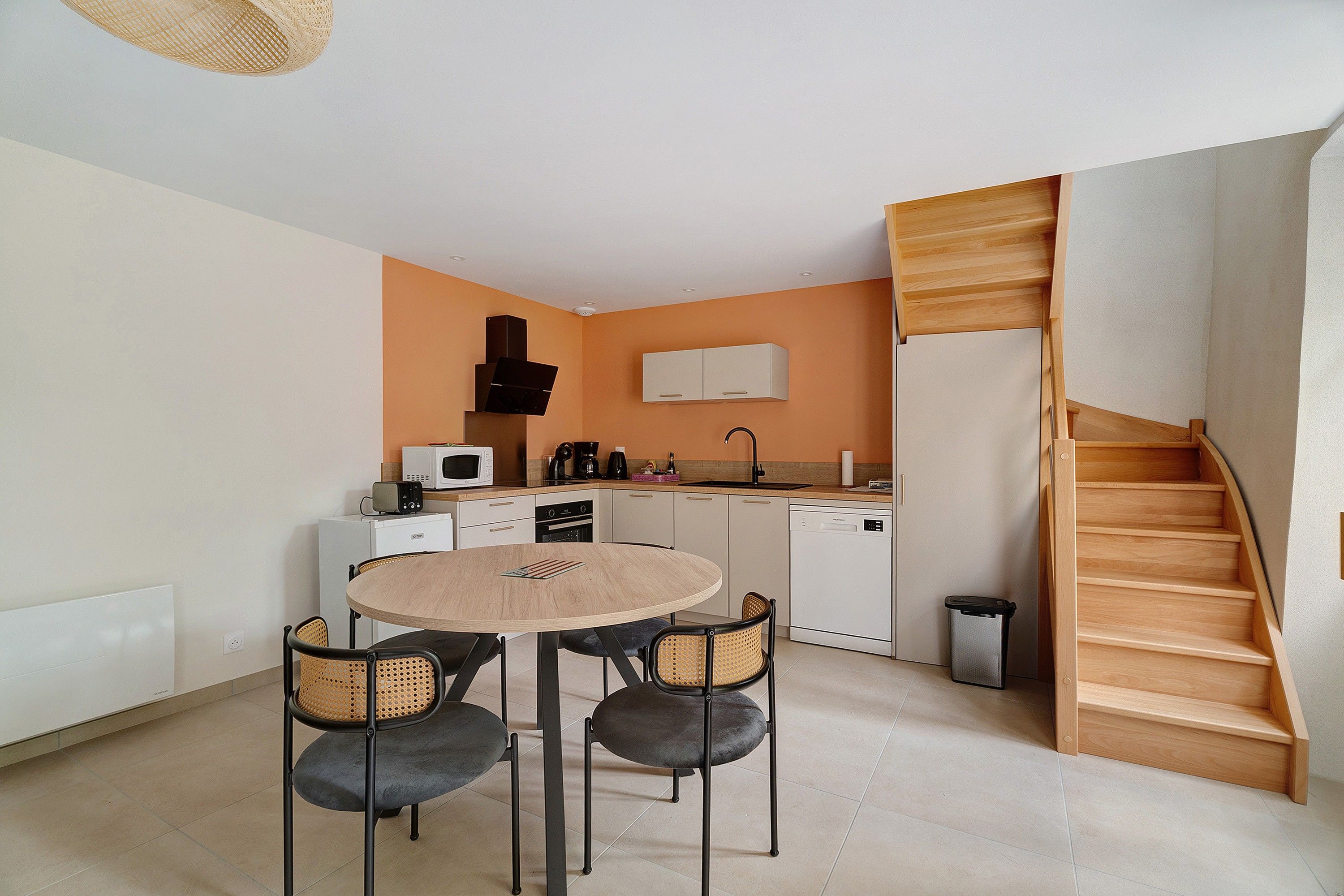 A compact kitchen with a dining area, white cabinets, a microwave, and a coffee maker.
