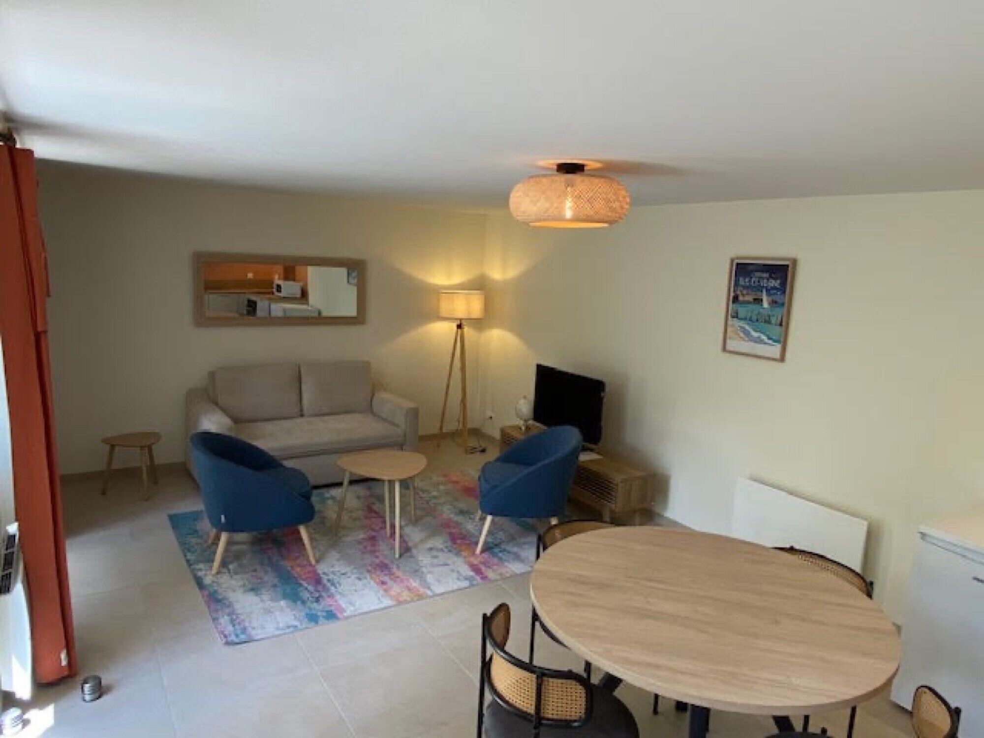 A living room with a sofa, two armchairs, a coffee table, a dining table, and a TV.