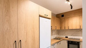 Una cucina con mobili in legno, un frigorifero bianco, un piano di lavoro con lavello e fornelli.