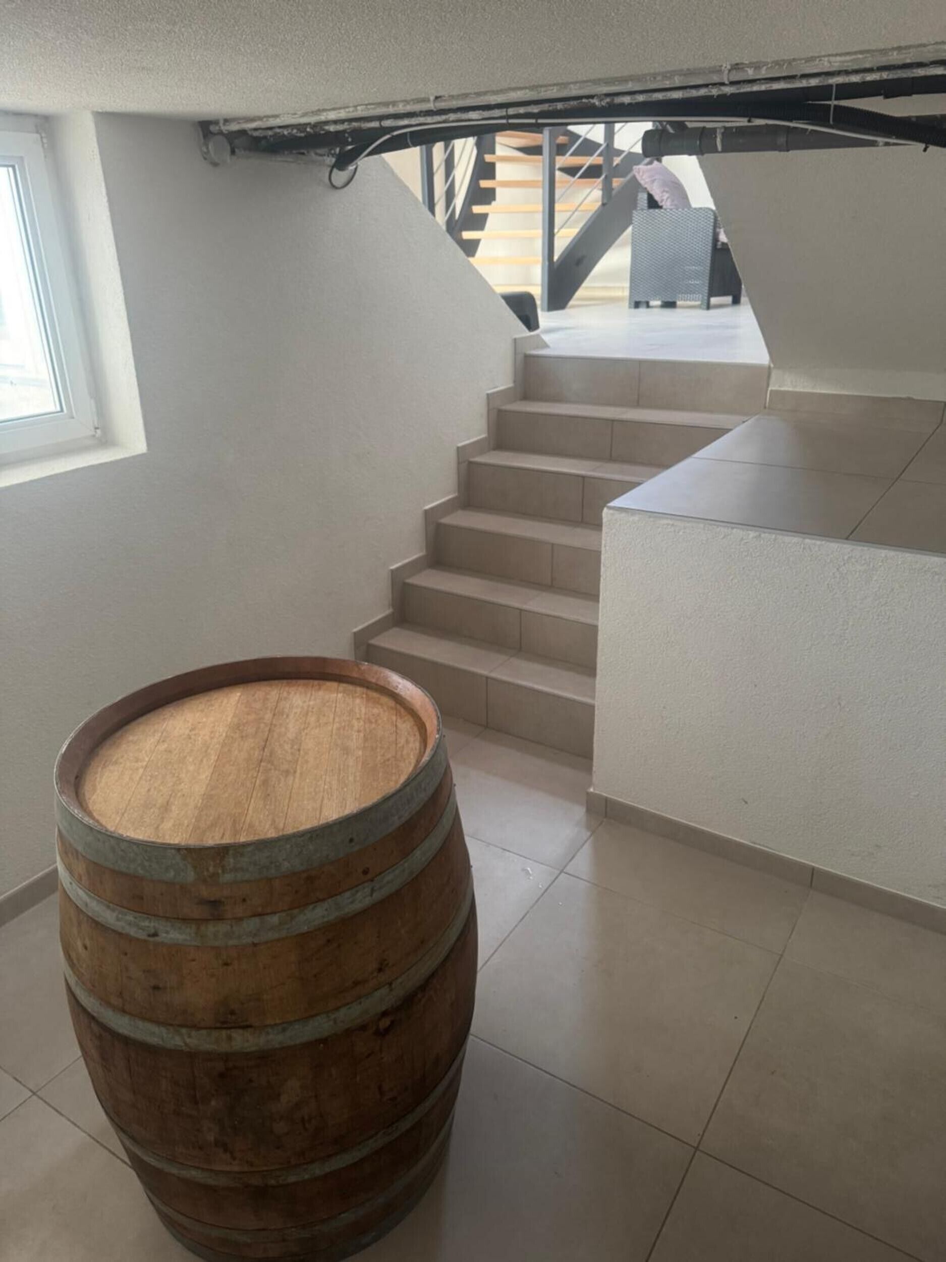 Eine Treppe mit einem hölzernen Fass in einem modernen Innenraum.