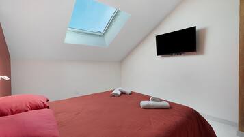 Ein Zimmer mit einem Bett, einem wandmontierten Flachbildfernseher und einem Oberlicht.