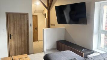 Una sala de estar moderna con un juego de sofá, una mesa de centro de madera y un televisor de pantalla plana montado en la pared.