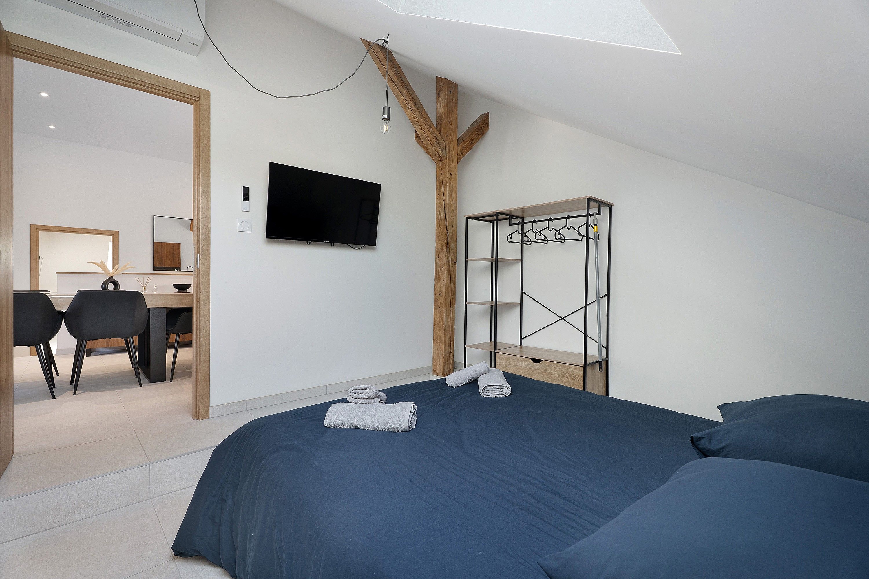 Een moderne slaapkamer met een groot bed, een bureau en een tv aan de muur.