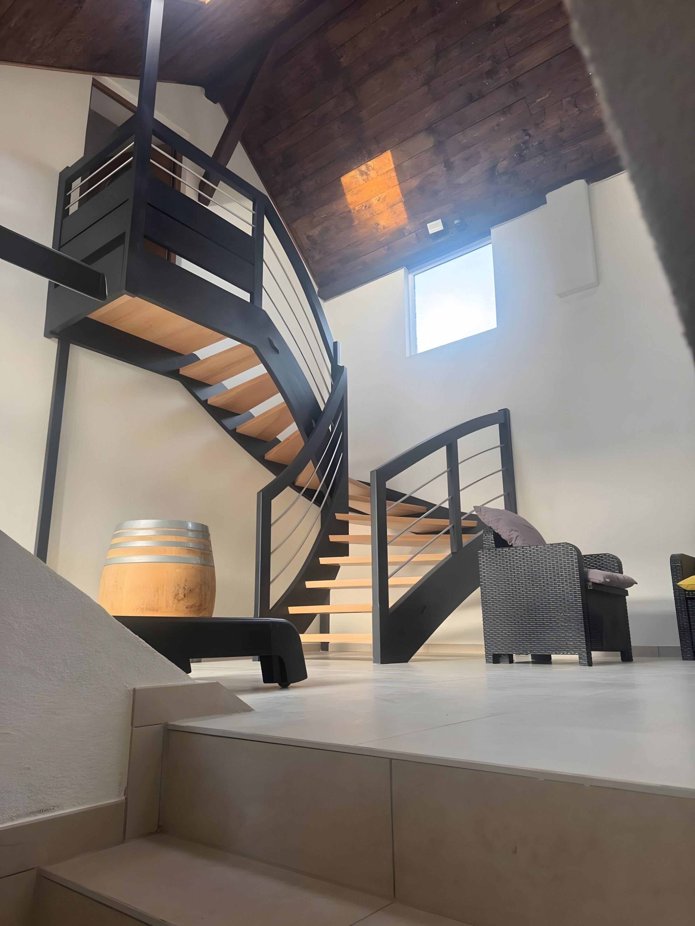 Ein modernes Interieur mit einer Wendeltreppe, einem Holzbottich und einer Couch.