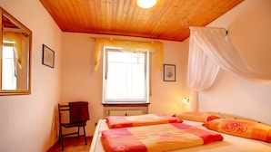 A room with two beds, a chair, a window, and a mirror.