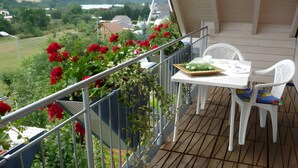 A balcony with a table and chairs, surrounded by greenery and flowers.