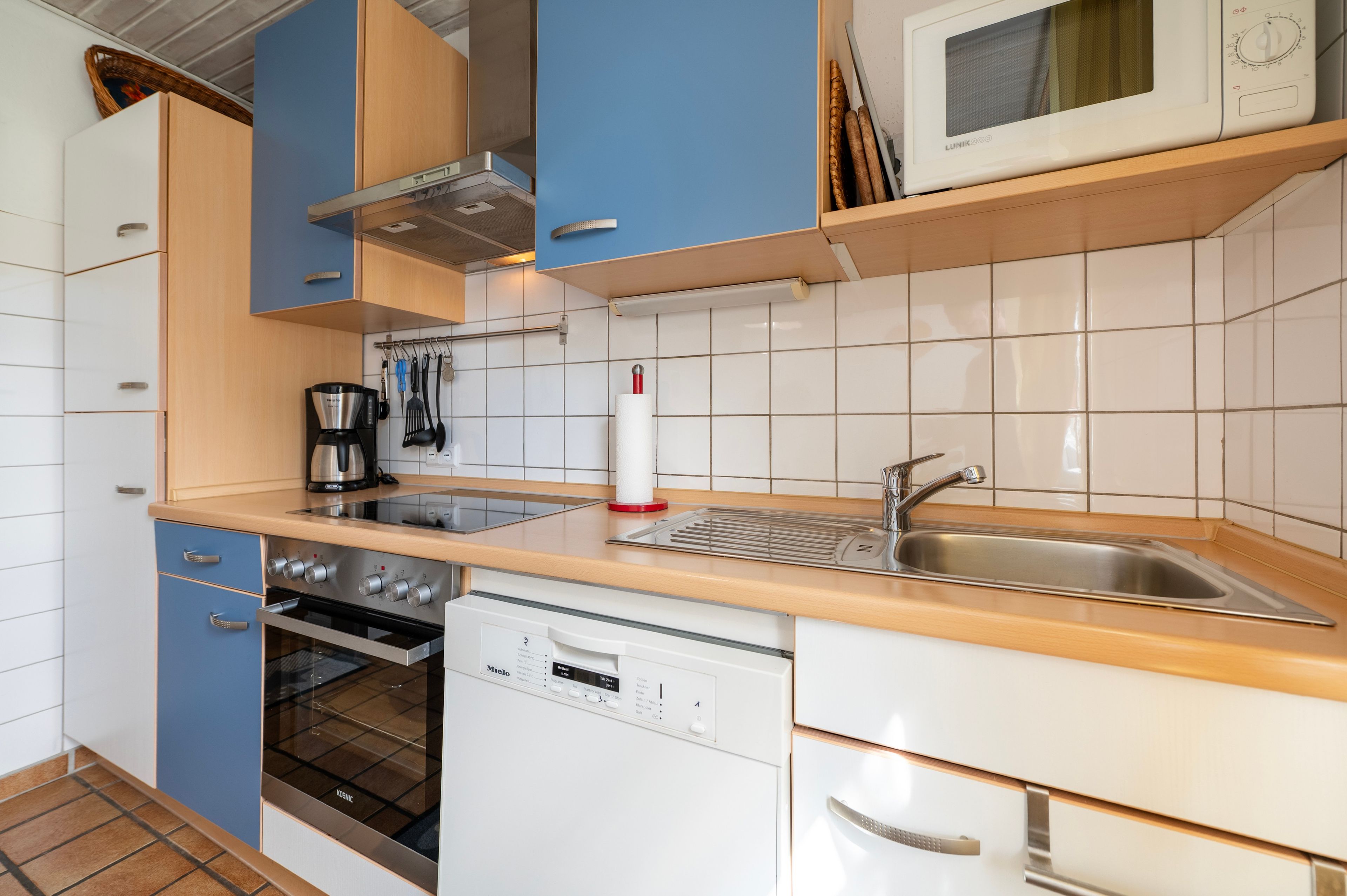 Een moderne keuken met een ingebouwde oven, vaatwasser en een magnetron op het aanrecht.