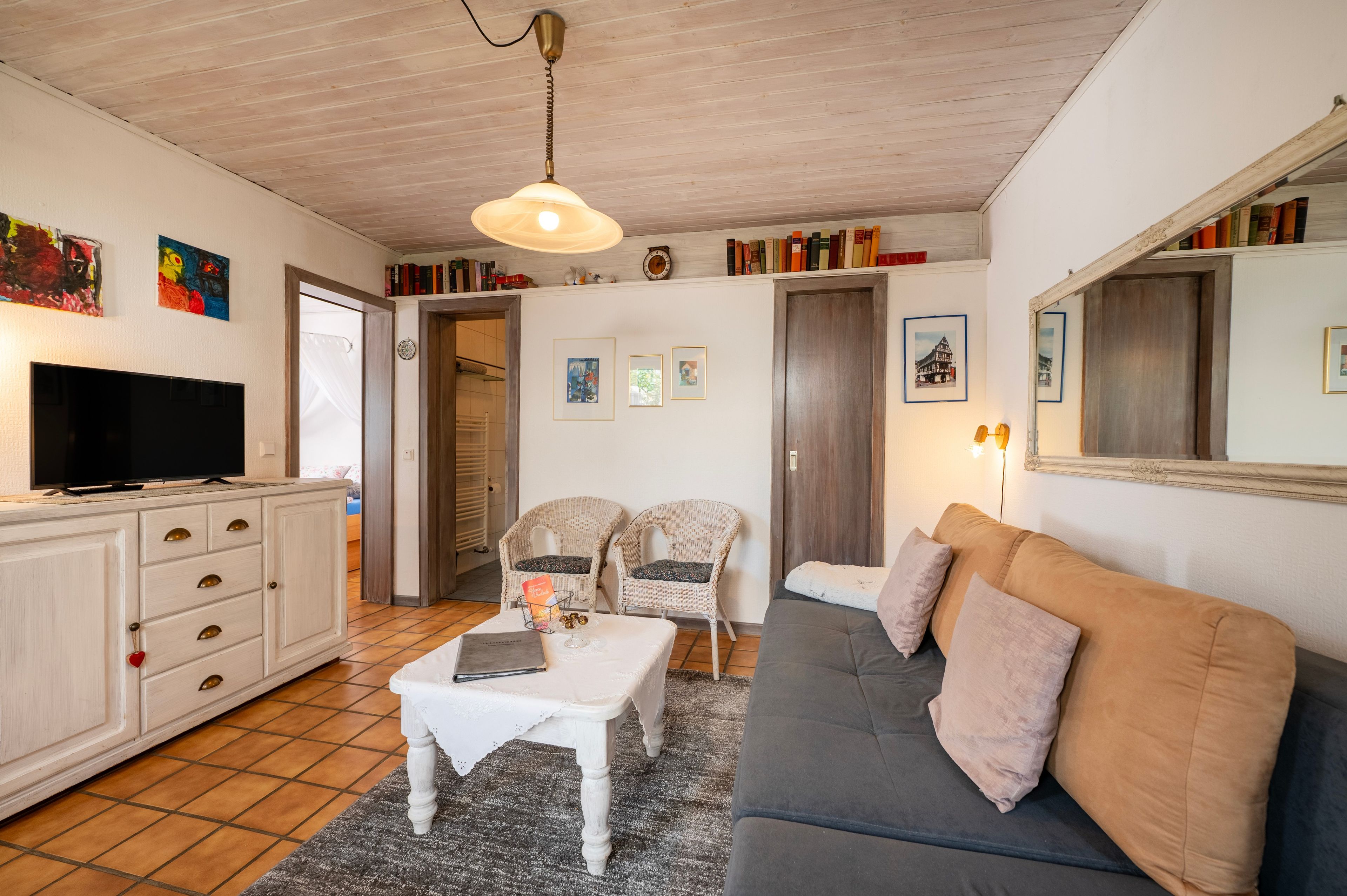 Ein gemütliches Wohnzimmer mit Fernseher, einer Couch, Sesseln und einem Couchtisch.