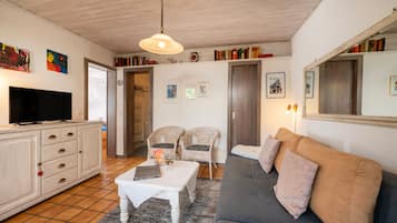 Ein gemütliches Wohnzimmer mit Fernseher, einer Couch, Sesseln und einem Couchtisch.