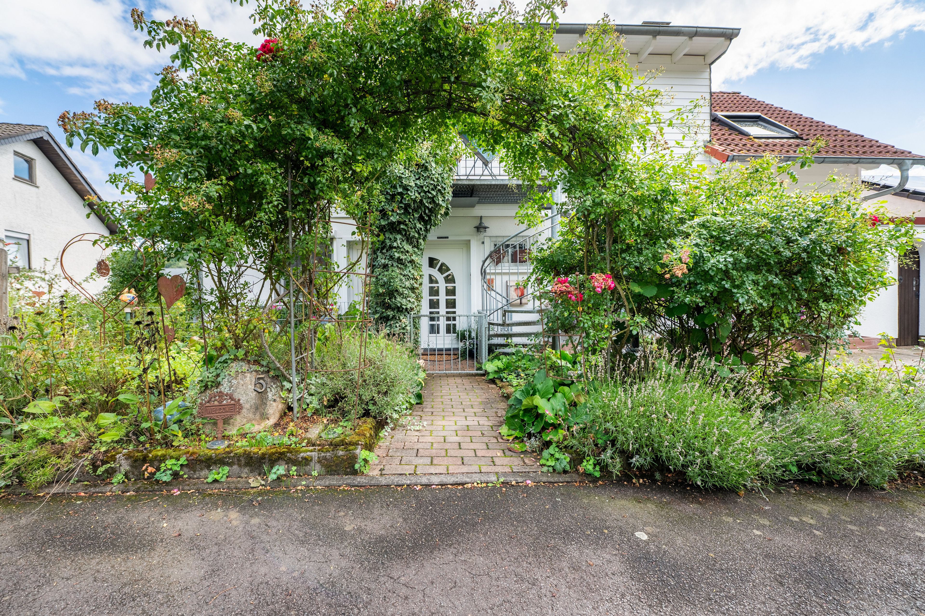 A garden entrance with a pathway leading to a house.