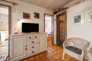 A room with a television on a cabinet, a wicker chair, and a bed in the background.