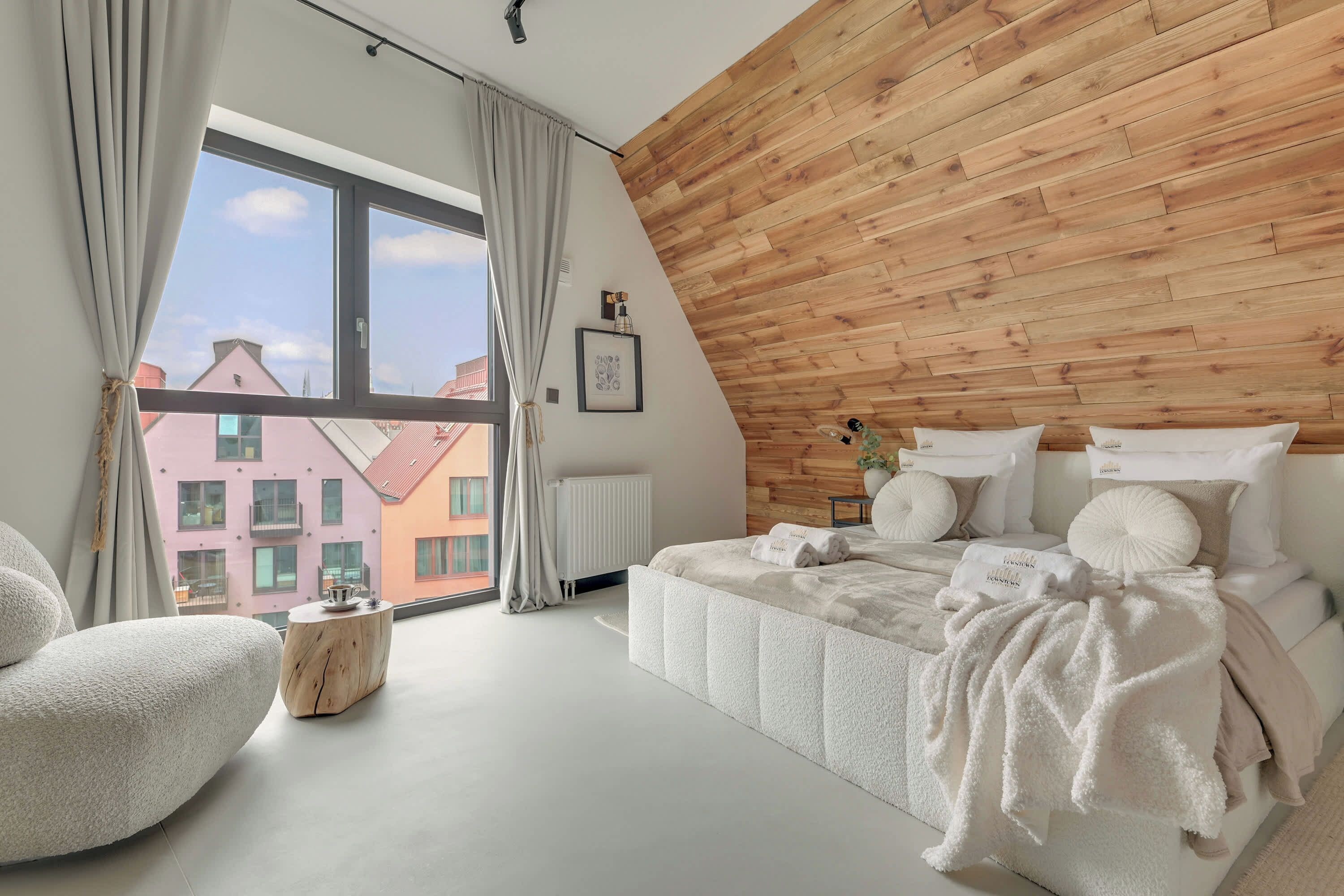 Quarto moderno com uma grande janela, parede de madeira e cama bem arrumada.
