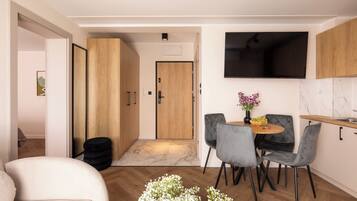 A compact living space with a dining area, a TV mounted on the wall, and a wooden door.
