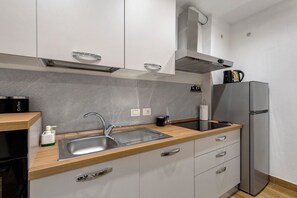 A modern kitchen with a stainless steel sink, wooden countertop, and a built-in refrigerator.