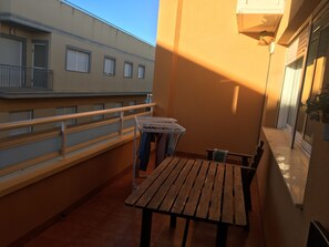 A balcony with a wooden table and chairs, a clothes drying rack, and a railing.