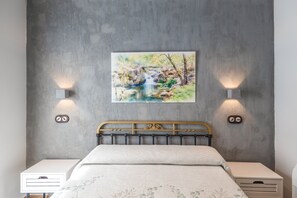 A bedroom with a bed, two bedside tables, a wall-mounted painting, and two wall sconces. - Tourist Home 'La Posada del Pueblo', Sotillo de las Palomas (Sotillo de las Palomas)