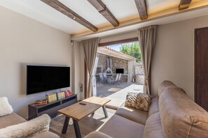Een moderne woonkamer met een flatscreen televisie, een houten salontafel en een bank.