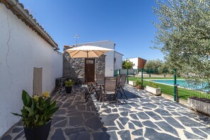 A patio area with stone flooring, outdoor furniture, and a pool in the background. - Rural House 'Casa Rural con Piscina Privada en Sotillo de las Palomas, Sierra de Gredos' (Sotillo de las Palomas)