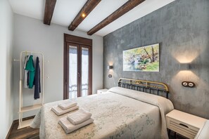 Een slaapkamer met een bed, een kledingkast, een schilderij en een wandlamp.