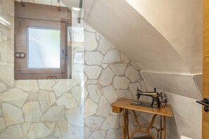 A room with a stone wall, a wooden door, and a sewing machine on a small table. - Rural House 'Casa Rural con Piscina Privada en Sotillo de las Palomas, Sierra de Gredos' (Sotillo de las Palomas)