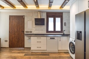 A modern kitchen with a dishwasher, a built-in oven, a window above the sink, and a wooden door. - Tourist Home 'La Posada del Pueblo', Sotillo de las Palomas (Sotillo de las Palomas)