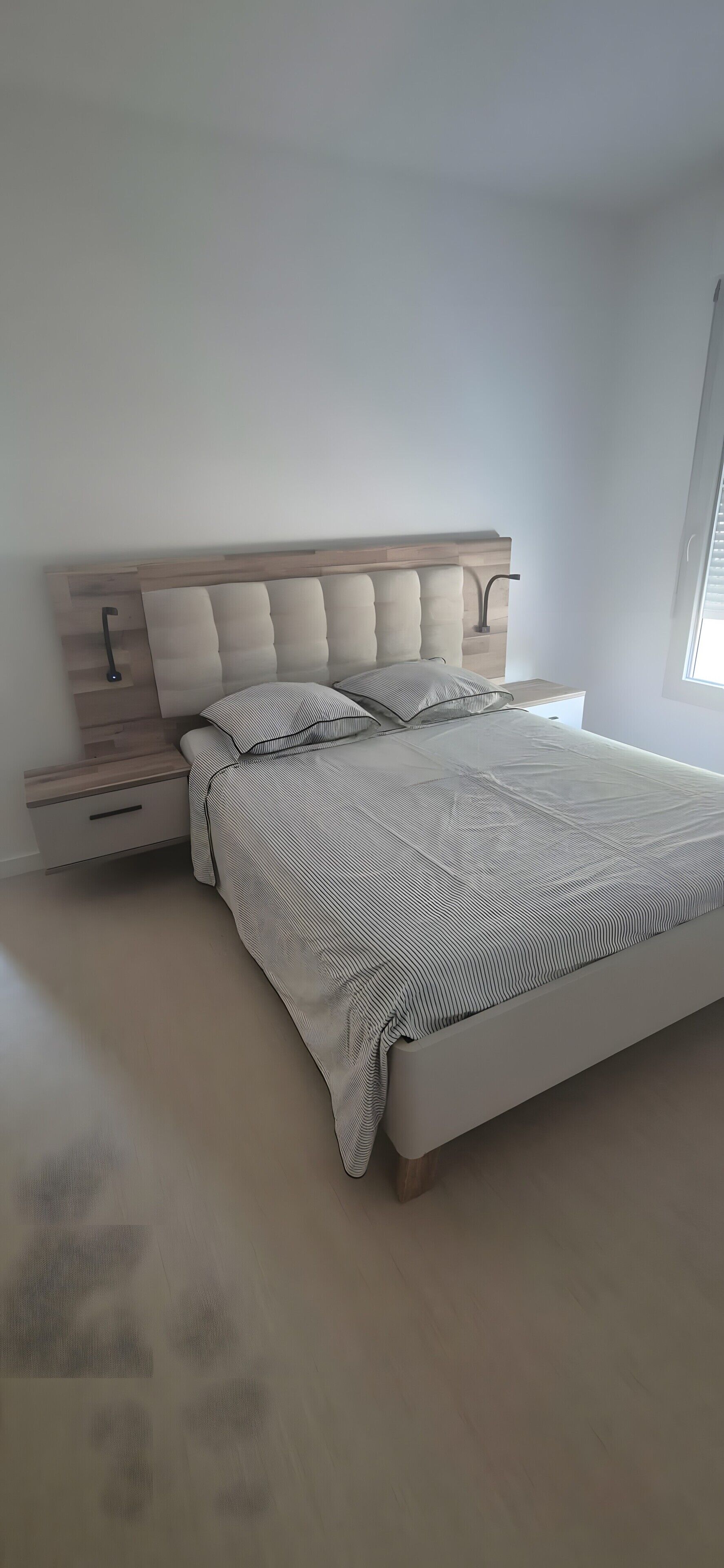 Een slaapkamer met een bed, nachtkastje en raam.