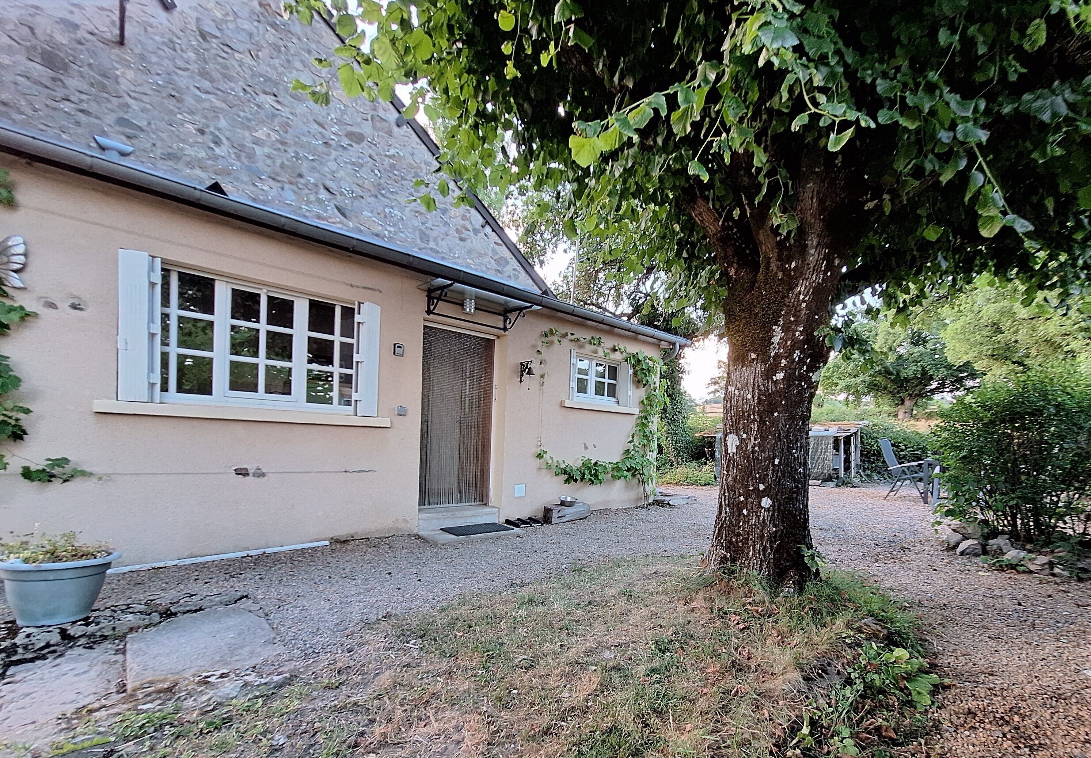 Une maison avec un toit en pierre, une porte en bois et une allée gravillonnée.