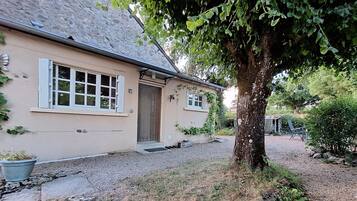 Une maison avec un toit en pierre, une porte en bois et une allée gravillonnée.