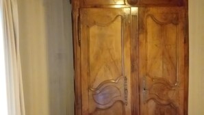 Un armario de madera con diseño clásico, ubicado en una habitación con piso de baldosas y techo de madera.