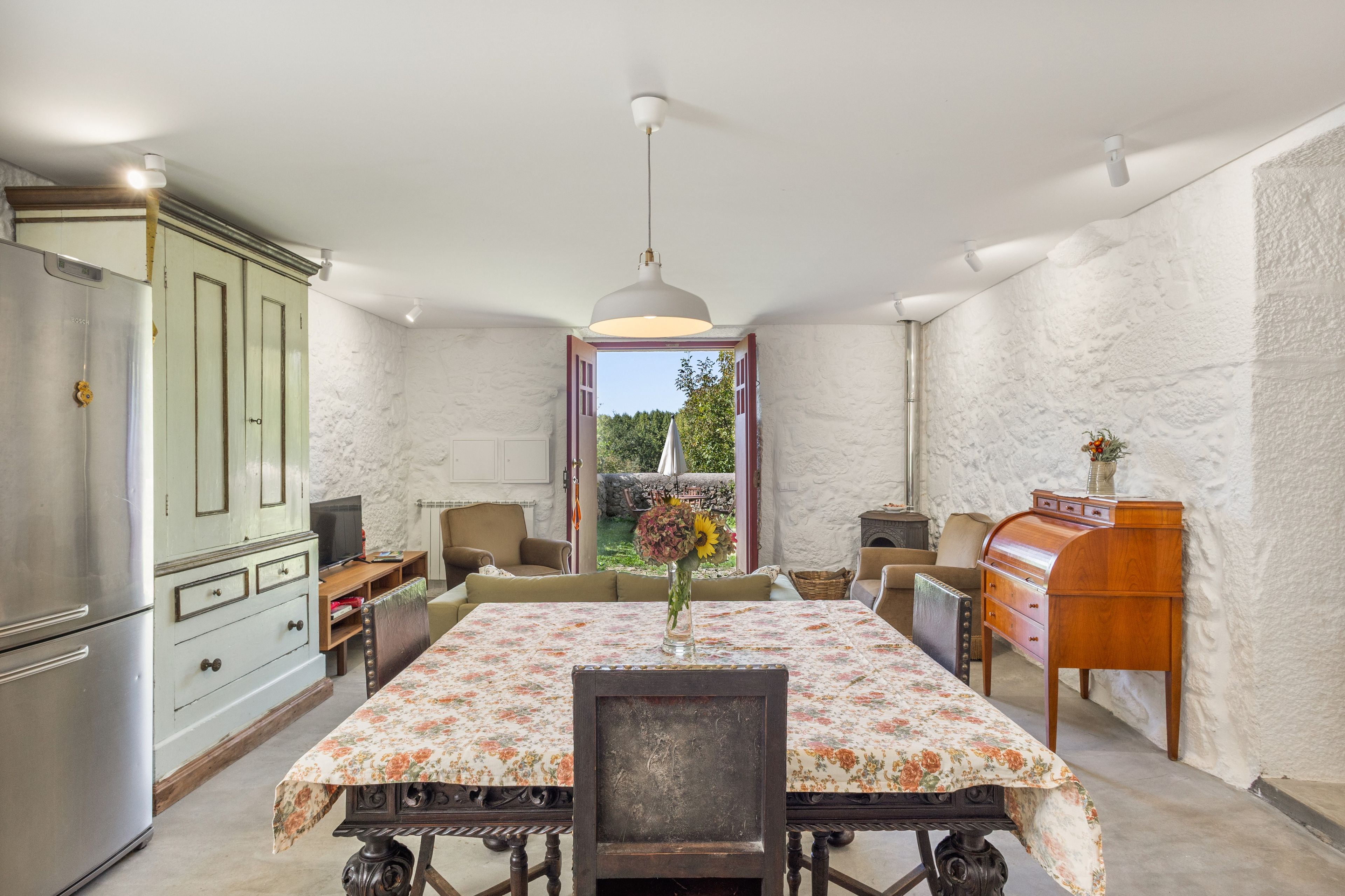 A dining area with a table set for two, a vintage-style cabinet, and a view of the outdoors.