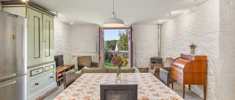 A dining area with a table set for two, a vintage-style cabinet, and a view of the outdoors.