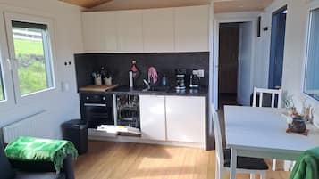 Eine kleine Küche mit weißen Schränken, einem eingebauten Backofen und einer Kaffeemaschine.