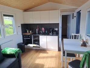 A compact kitchen with white cabinets, a built-in oven, and a coffee maker. - Tiny Home 'Haus Hecht' with Lake View, Wi-Fi, and Air Conditioning (Lohmen)