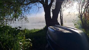 A boat parked under a tree by a body of water with mist in the background.