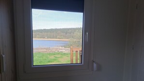 A room with a window overlooking a lake and a grassy area.