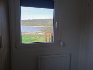 A room with a window overlooking a lake and a grassy area.