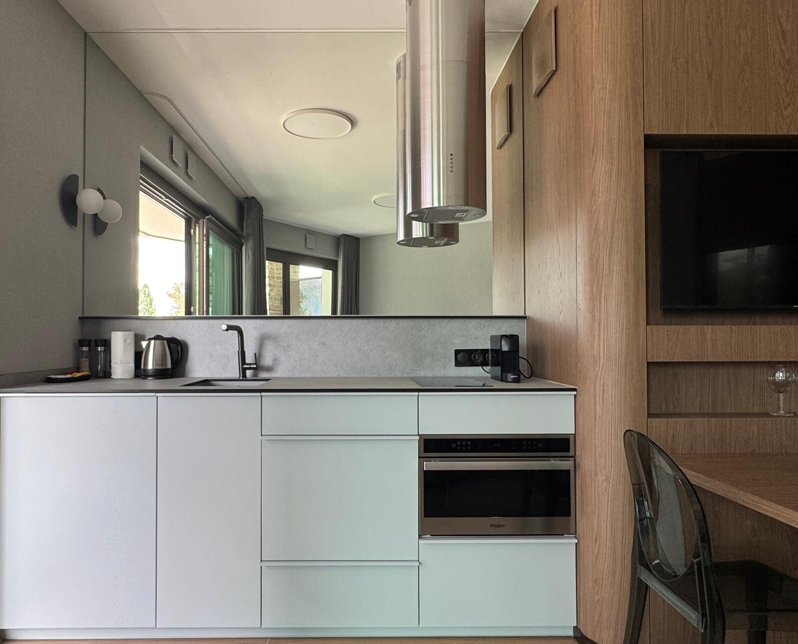 Una cocina moderna con horno integrado, cafetera y un espejo grande.