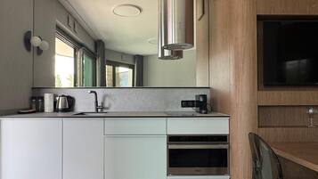 Una cocina moderna con horno integrado, cafetera y un espejo grande.