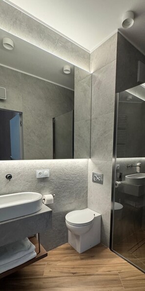 A modern bathroom with a large mirror, a toilet, a sink, and a shower area. - LILY ART with wine - Gdansk Shipyard & Rooftop Terrace by Lily Apart (Gdańsk)