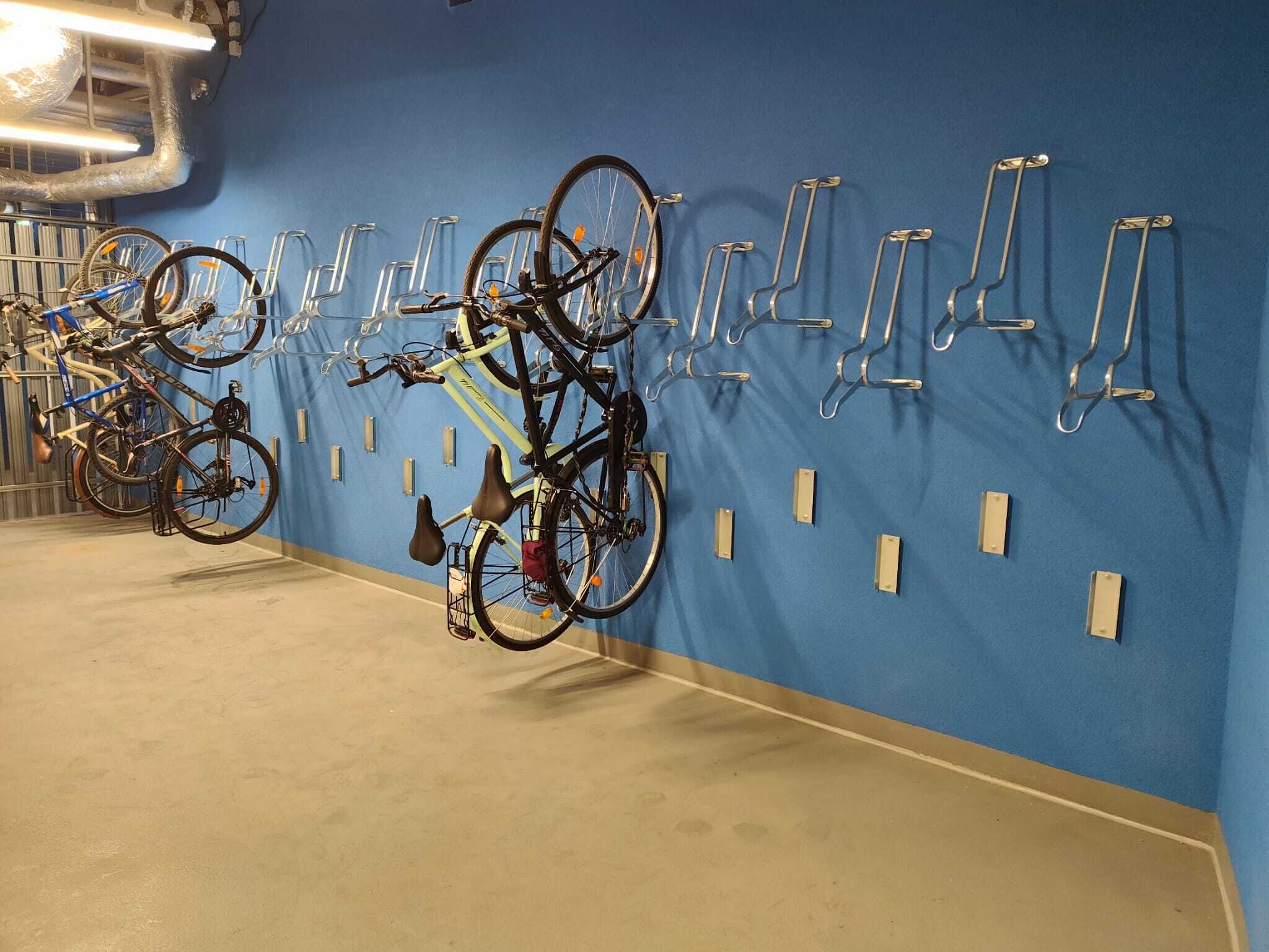 Un área de estacionamiento para bicicletas con varias bicicletas aseguradas a soportes fijados a la pared.
