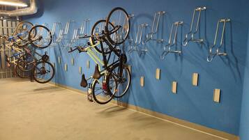 Un área de estacionamiento para bicicletas con varias bicicletas aseguradas a soportes fijados a la pared.