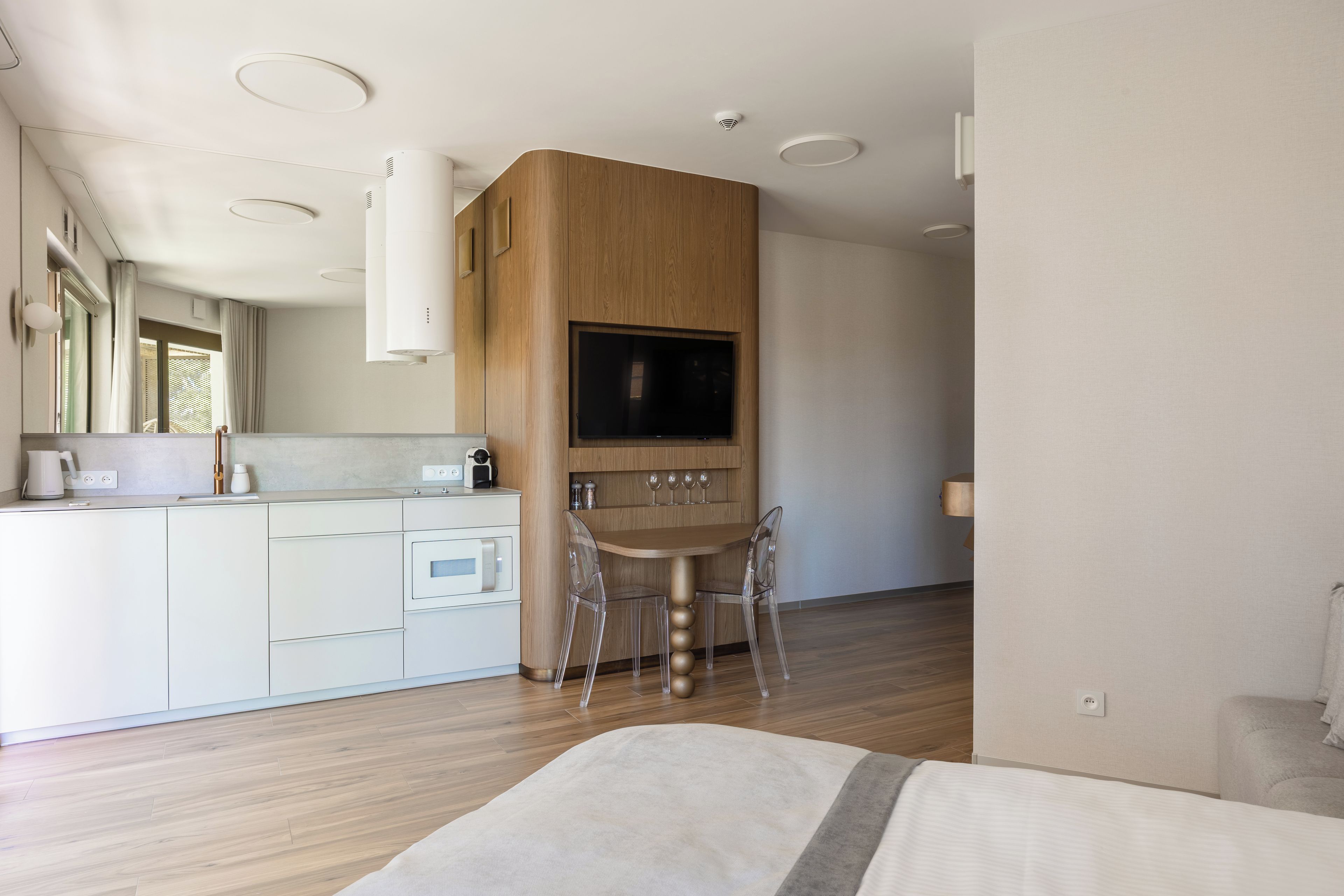 Una cocina moderna con televisión integrada, armarios de madera y un comedor con mesa y sillas.