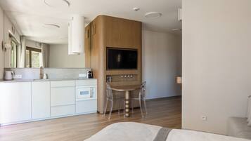 Una cocina moderna con televisión integrada, armarios de madera y un comedor con mesa y sillas.