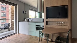 Ett modernt kök med en inbyggd TV, träinredning och en matplats med stolar.