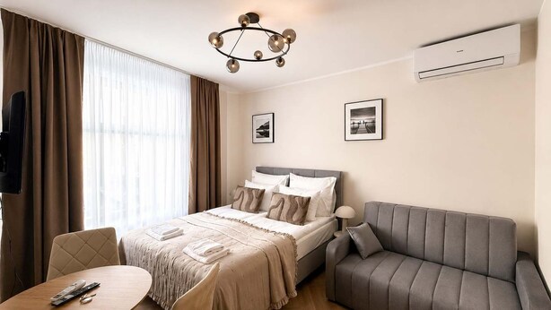 A hotel room with a bed, a sofa, a table, and a TV. - Kraków Bohaterów Września 8 | AC | Parkside (Kraków)